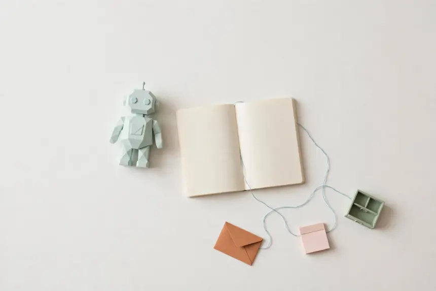 Flat-lay: small mint robot figurine beside an open notebook with a blue thread connecting to tiny pastel tool props, symbolizing an AI agent orchestrating narrow tools