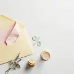 Flat-lay: open pastel-yellow envelope with a blush-pink letter, a mint percentage-sign cutout, gold coins and a wax seal stamp