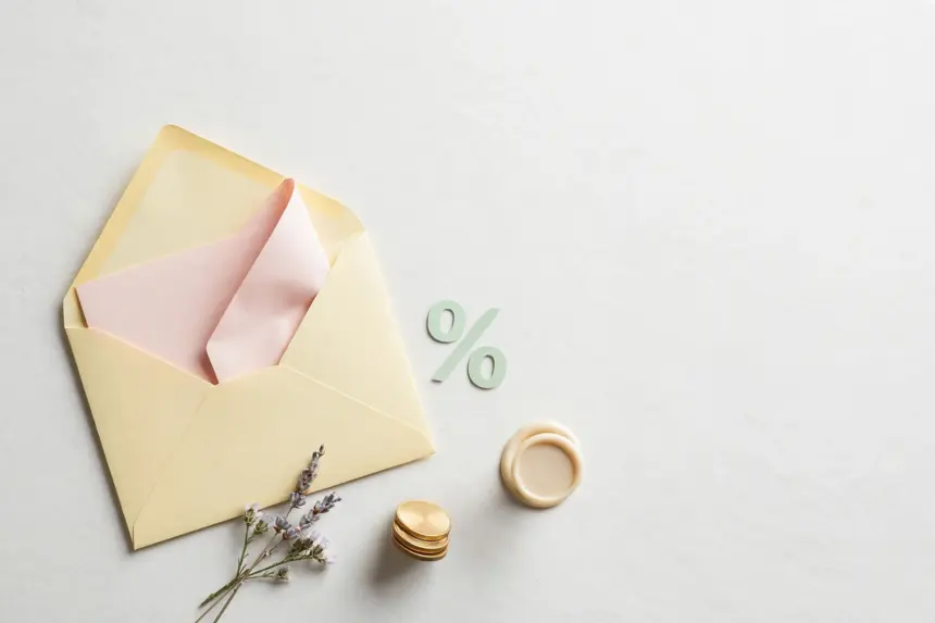 Flat-lay: open pastel-yellow envelope with a blush-pink letter, a mint percentage-sign cutout, gold coins and a wax seal stamp
