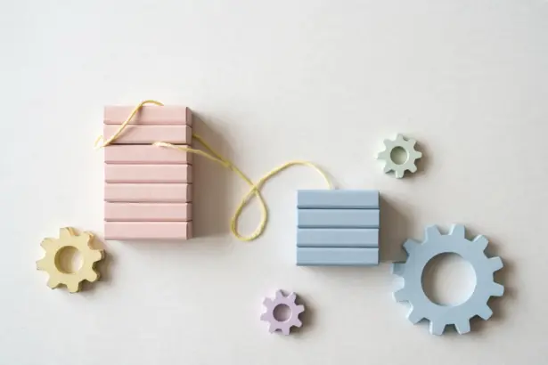 Flat-lay: two stacks of pastel wooden blocks, a tall blush pink beside a shorter powder blue, connected by pale yellow string, symbolizing the underdog challenger