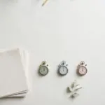 Flat-lay: a neat stack of blank paper reports beside a row of three small pastel stopwatches in mint, blue and pink on a pale off-white background