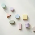 Flat-lay: a small market stall shelf holding nine tiny pastel jars and boxes of different shapes in a row on a pale off-white background