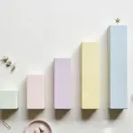 Flat-lay: a row of small ascending bar-chart blocks in pastel wood on a pale off-white background, the tallest block topped with a tiny brass star