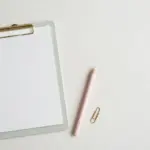 Pastel clipboard with blank score sheet and pencil — benchmarking an AI support agent